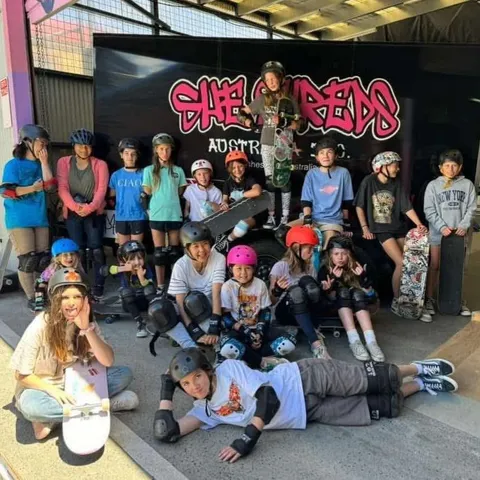 She Shreds skaters group photo under the She Shreds banner