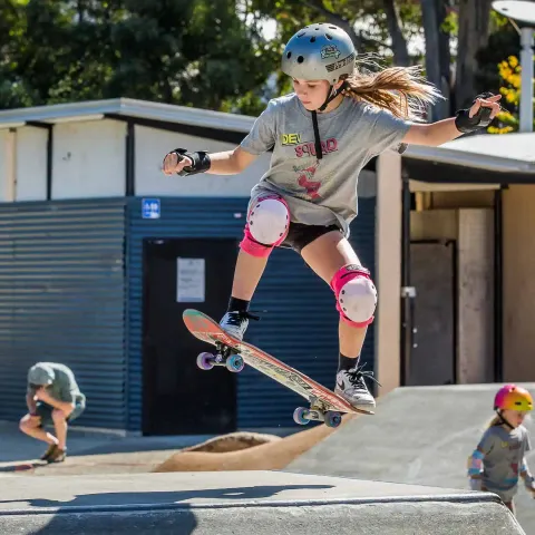 Skater in a grey Dev Squad shirt and pink pads doing an ollie