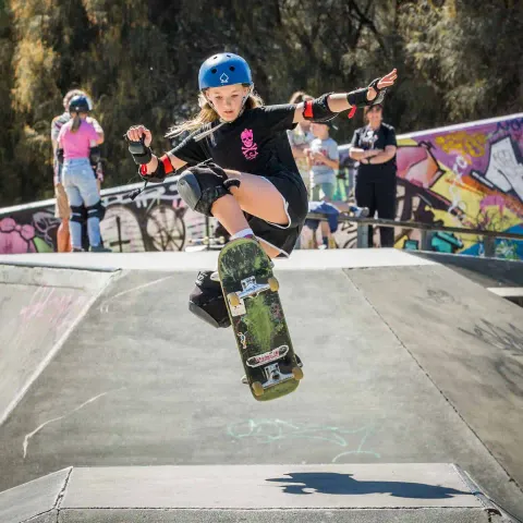 Skater in a blue helmet and skull shirt doing an ollie
