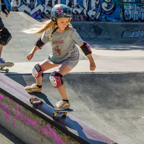 Skater dropping in on a ramp wearing pink leopard pads